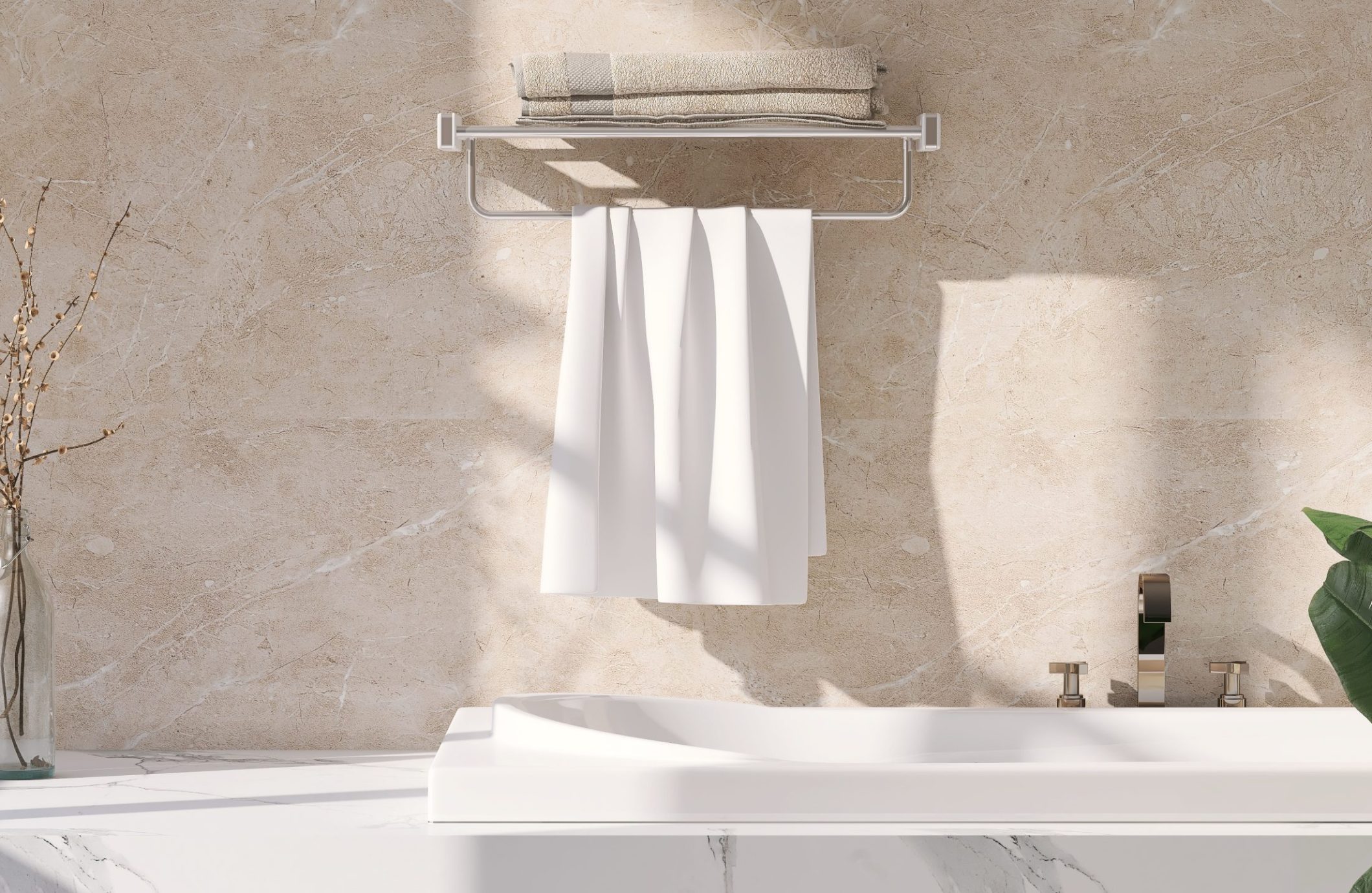 A modern bathroom with beige marble walls and countertop. A white towel hangs neatly from a metal towel rack, and folded beige towels are placed on top. A faucet and plant are visible on the right, with a vase holding branches on the left. Bright natural light illuminates the scene.